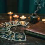 Vous ne comprenez pas vos cartes ? Les erreurs à éviter en cartomancie Jeu de cartes divinatoires posé sur une table sombre, avec un carnet de notes et une ambiance ésotérique feutrée, éclairage de bougies et fumée légère.